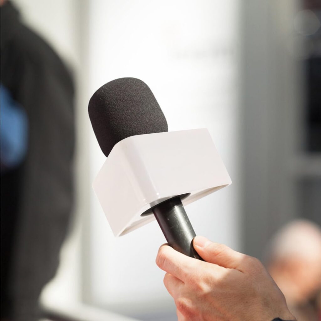 Blank white triangular microphone flag on a handheld microphone with black foam windscreen, unbranded mic flag for custom logo printing.