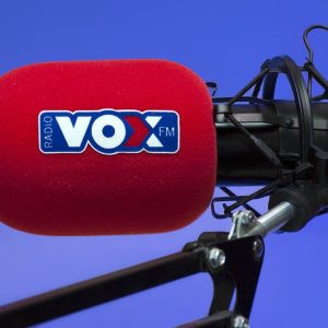 Radio VOX FM branded studio microphone windshield with red cylindrical foam cover and blue-white logo